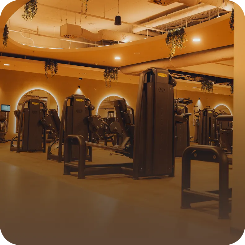 Modernes Fitnessstudio mit Kraftgeräten, Bogenfenstern und warmem Licht im Peoples Fitness Studio